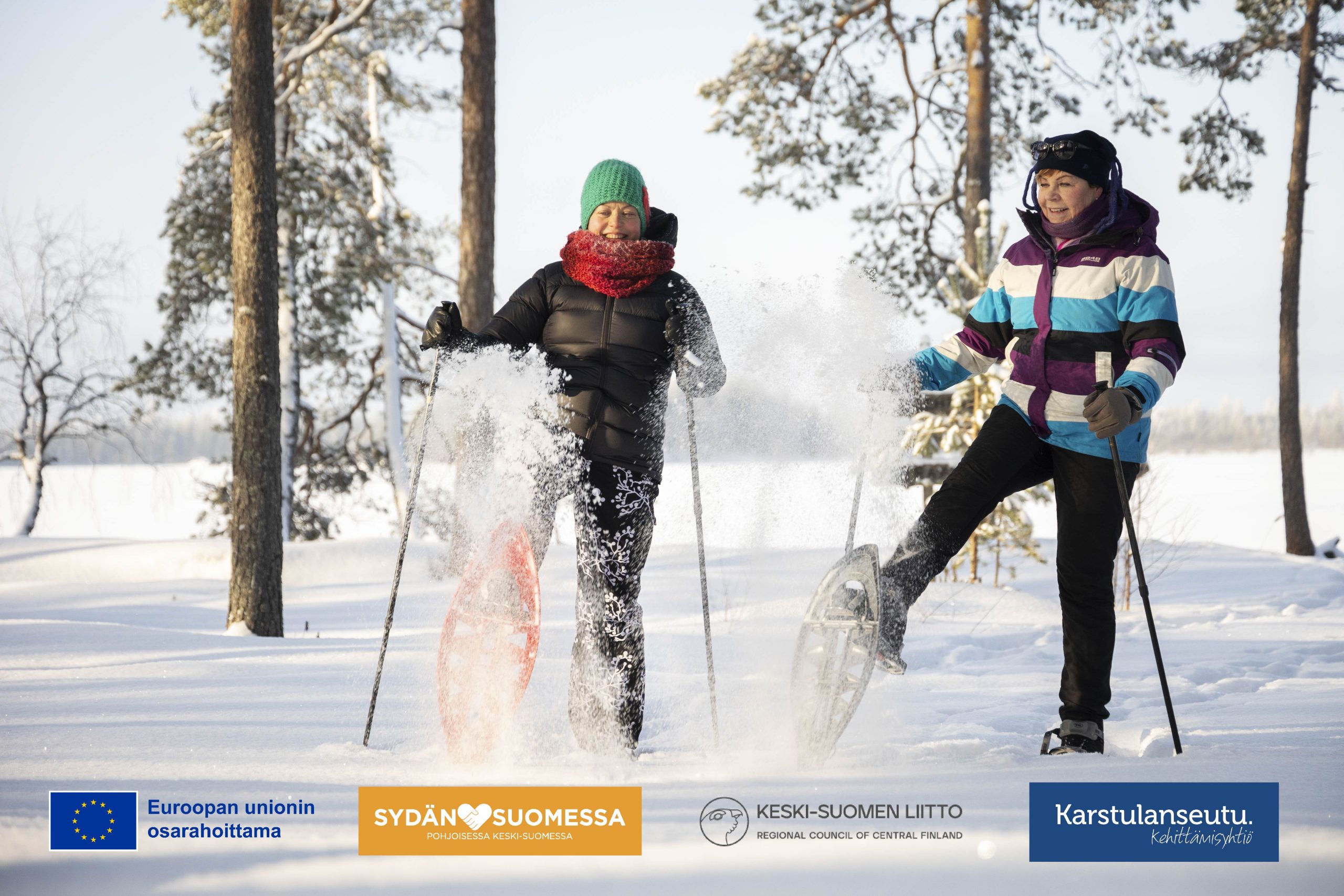 Kaksi henkilöä lumisessa metsässä lumikengillä, EU:n osarahoittama, Sydänsuomessa, Keski-Suomen liitto, Kehittämisyhtiö Karstulanseutu -logot